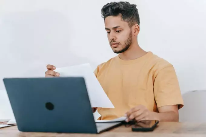 prinsjesdag 2023 Man achter laptop lees op papier