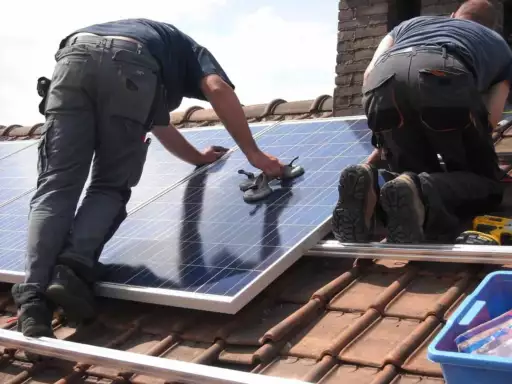 Mannen plaatsen zonnepanelen op dak