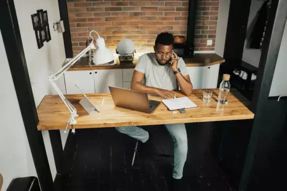 Man zit bellend achter bureau met laptop