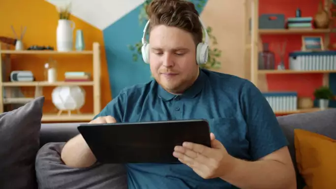 Man met koptelefoon gebruikt internet op tablet