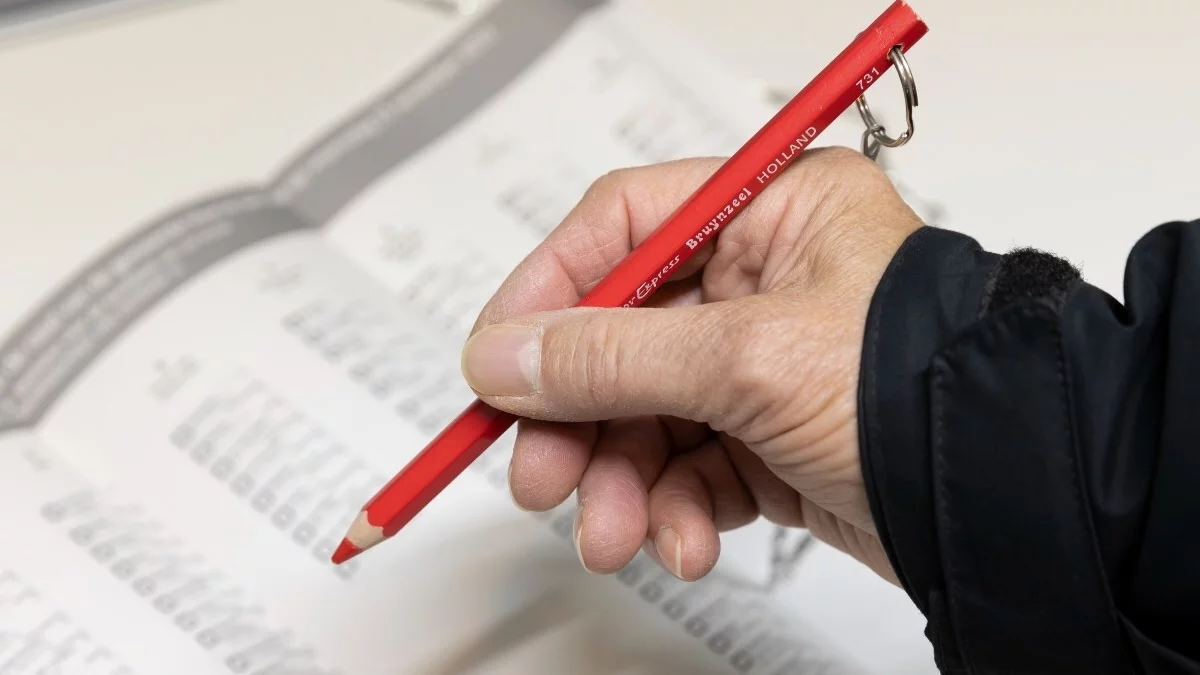 Foto van iemand met een rood stempotlood die een keuze maakt op een stembiljet