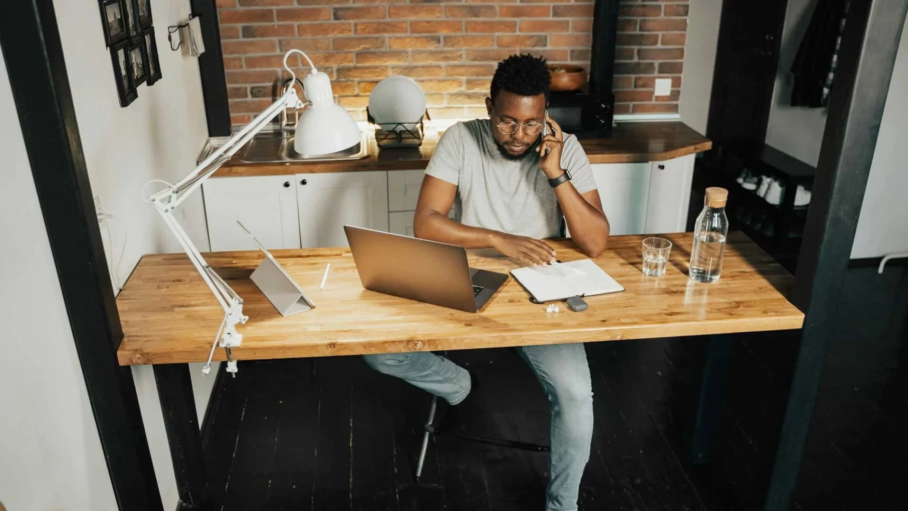 Man zit bellend achter bureau met laptop