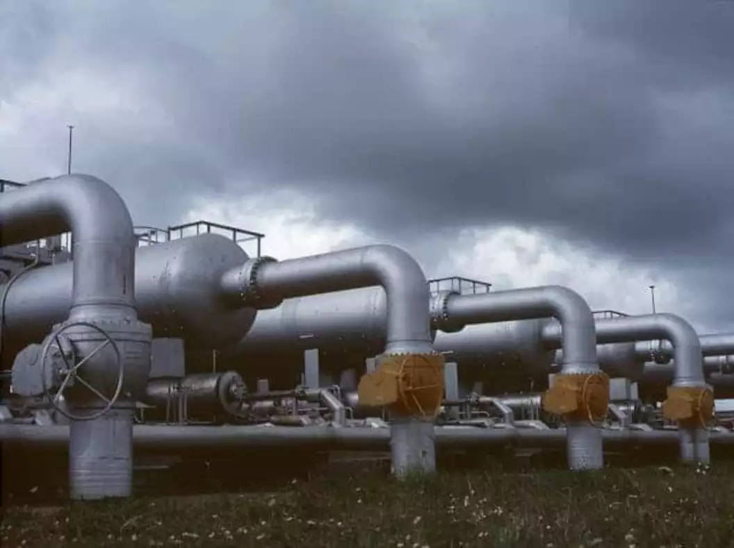 Foto van een gasinstallatie met een donkere wolkenlucht op de achtergrond.